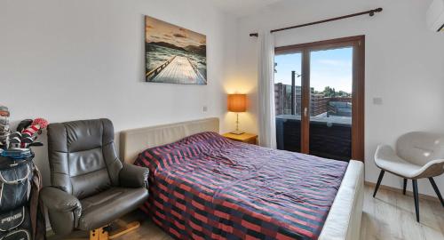 a bedroom with a bed and a chair and a window at Villa HG08 Pyrinas in Kouklia