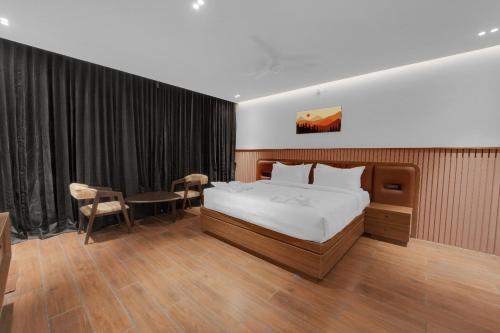 a bedroom with a bed and a table and chairs at The Forest Glen by TIO Hotels in Yercaud