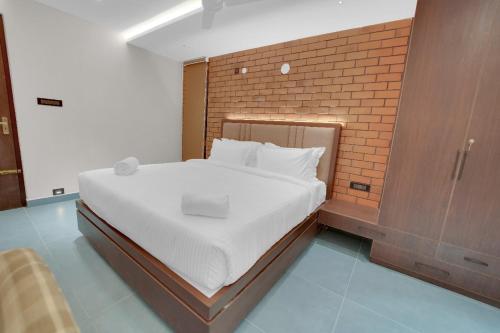 a bedroom with a large bed with a brick wall at The Forest Glen by TIO Hotels in Yercaud
