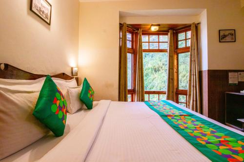 a bedroom with a large white bed with green pillows at Treebo The Alpine Heritage Residency in Shimla