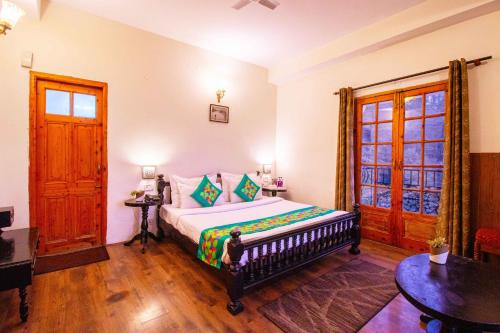 Treebo The Alpine Heritage Residency في شيملا: غرفة نوم بها سرير كبير في الغرفة