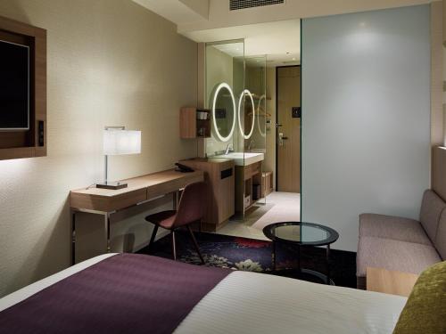 a hotel room with a bed and a desk and a sink at Millennium Mitsui Garden Hotel Tokyo - Ginza in Tokyo