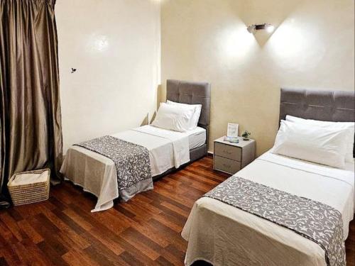 two beds in a room with wooden floors at Maison Ali in Ville Nouvelle