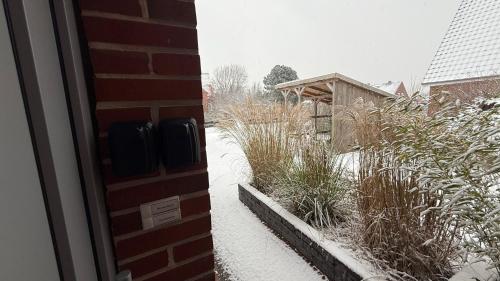 a house with snow on the ground next to a yard at Dünenhus Borkum in Borkum