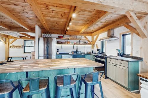 a kitchen with wooden ceilings and a large island with bar stools at Timber Riverhouse in Readsboro