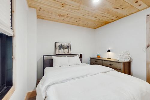 a bedroom with a white bed and a wooden ceiling at Timber Riverhouse in Readsboro