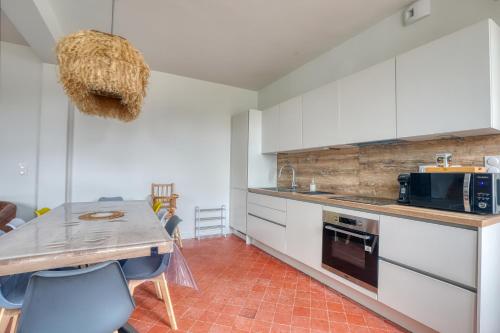 une cuisine avec des armoires blanches et une table avec des chaises dans l'établissement Maison spacieuse pour 8 personnes avec jardin, à Saint-Germain-la-Poterie