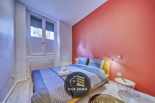 une chambre avec un lit et un mur rouge dans l'établissement Le Sembat-T2 Cosy hyper centre, à Grenoble