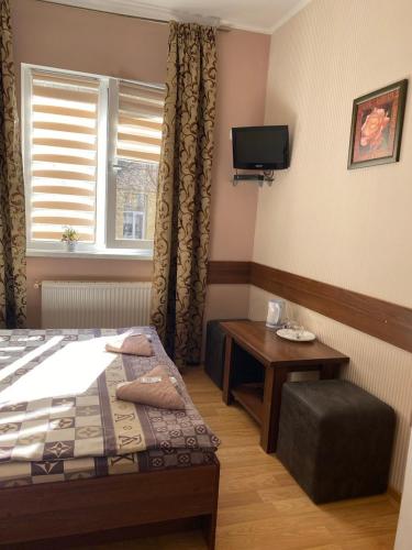 a bedroom with a bed and a table and a tv at Відпочинковий комплекс,міні готель Старий дворик in Lviv