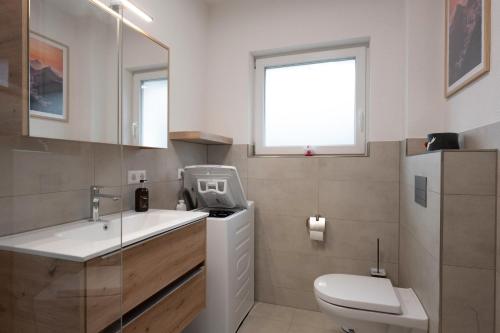 a bathroom with a sink and a toilet and a window at Corner 28 in Oberkirch