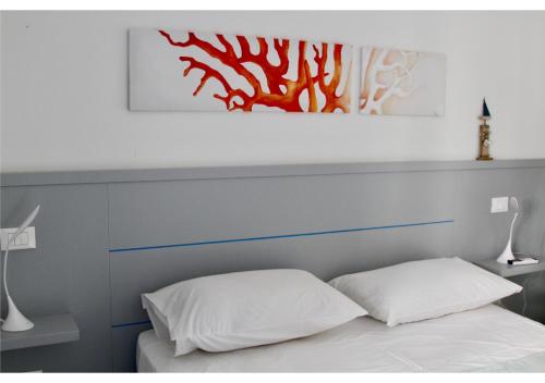 a bed with two pillows and a painting above it at Marina29- Appartamento C in Castelsardo