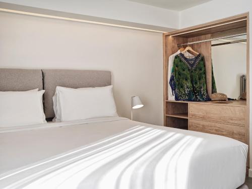 a bedroom with a white bed and a dresser at NLH Mati Seafront - Neighborhood Lifestyle Hotels in Mati