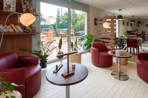 une salle d'attente avec des chaises et des tables rouges dans un magasin dans l'établissement Campanile Albi Centre, à Albi