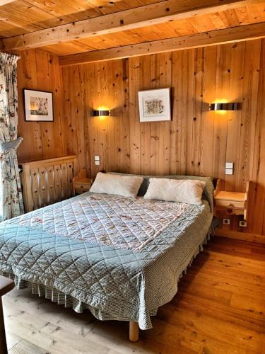 une chambre avec un lit dans une pièce aux murs en bois dans l'établissement Chez Fernande, à Notre-Dame-de-Bellecombe
