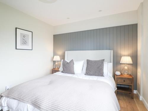 une chambre avec un grand lit blanc et deux lampes dans l'établissement Holm Oaks Cottage, à Godalming