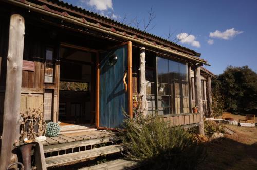 a house with a blue door on a porch at Yamakujira 焚火とBBQを楽しめる海辺プライベートコテージ 山鯨荘 in Minamiboso