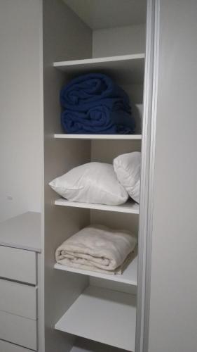 a closet with white shelves with pillows and a blue towel at Frente al mar in Pinamar