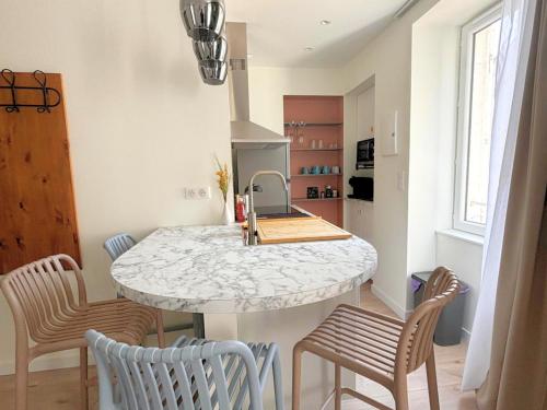 - une cuisine avec un comptoir en marbre et des chaises dans l'établissement Les Sapins, T2 hyper centre avec climatisation, à Lons-le-Saunier