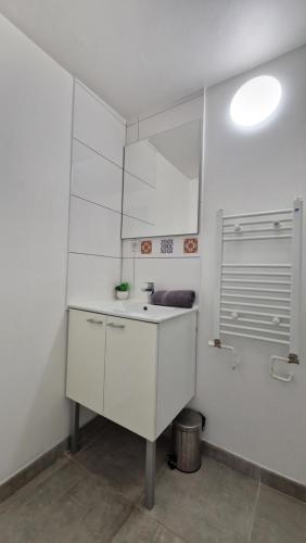 une salle de bain blanche avec un lavabo et un miroir dans l'établissement Le Cosy Hyper Centre d'Orléans, à Orléans