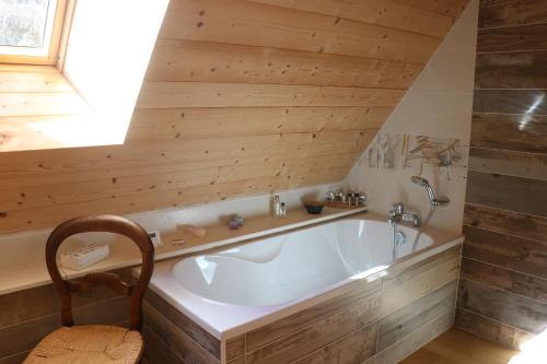 a bath tub in a room with a wooden ceiling at La Fermette de Loucheyre in Saint-Amandin