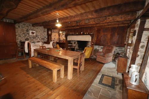 - un salon avec une table en bois et une cheminée dans l'établissement La Fermette de Loucheyre, à Saint-Amandin