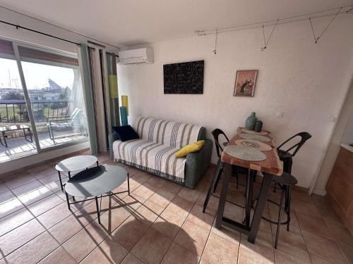 un salon avec un canapé, une table et des chaises dans l'établissement Studio moderne avec climatisation et parking proche plage - FR-1-731-132, au Grau-du-Roi