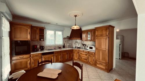 une cuisine avec des armoires en bois et une table en bois dans l'établissement Maison proche centre ville, cosy et confort, à Saint-Jean-de-Monts