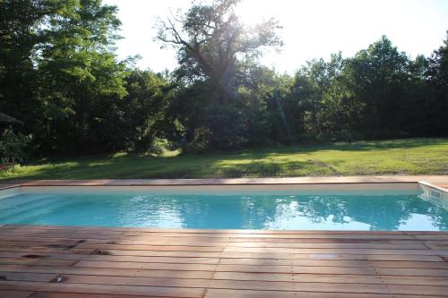 - une piscine avec une terrasse en bois à côté d'une cour dans l'établissement maison Jus, à Lesgor