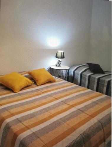 a bedroom with two beds and a table with a lamp at Appartement confort in Île de Diane