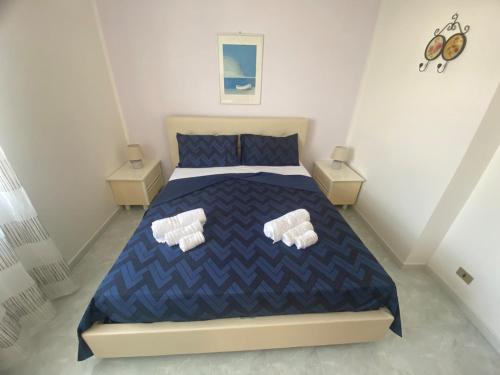 a bedroom with a blue bed with two white pillows at Casa dei Fiori sul mare, terrazza esclusiva in Stazione di San Sostene