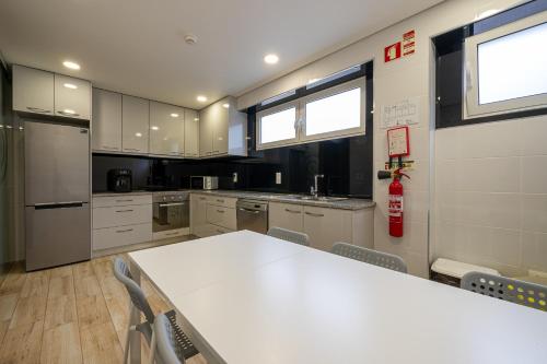 a large kitchen with a white table and chairs at Central Suites in São João da Madeira