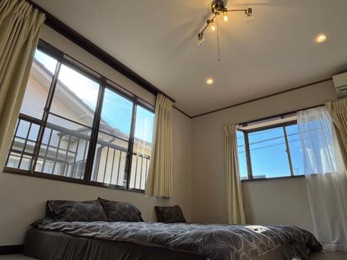 a bedroom with a bed and large windows at 青梅森の宿 in Ome