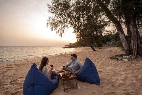 a man and woman sitting at a table on the beach at Koh Russey Resort in Koh Russey