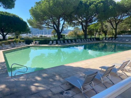 une grande piscine avec des chaises et des arbres dans l'établissement Appartement T2 Residence front de mer, à Mandelieu-la-Napoule