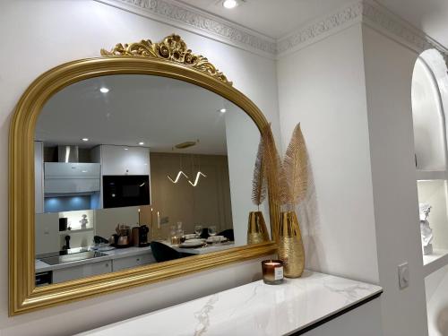 un miroir en or dans une pièce blanche avec une cuisine dans l'établissement Résidence Auguste Comte - avec Balcon - Cœur de Dijon, à Dijon