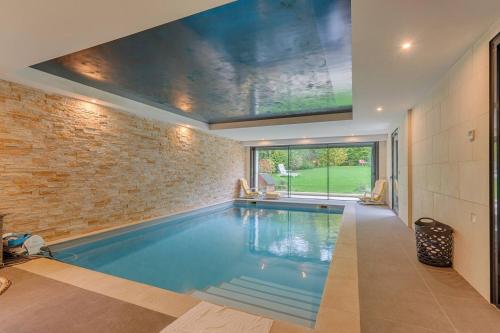 - une piscine dans une maison dotée d'un mur en briques dans l'établissement Villa Luxe vallée de Chevreuse - Piscine intérieure chauffée - 14 pers - Le relais des clefs, à Chevreuse