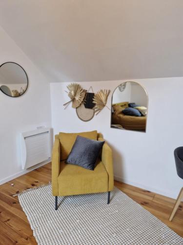 - un salon avec une chaise jaune et un miroir dans l'établissement La grange de l'Ailette, à Neuville-sur-Ailette