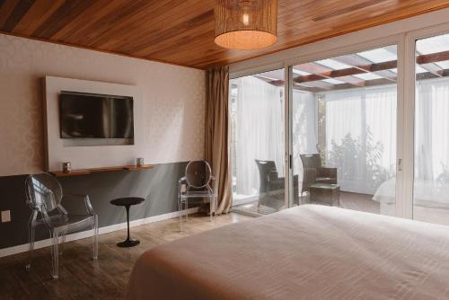 a bedroom with a bed and a tv and chairs at Puerto Dijama Hotel Boutique in Carmelo