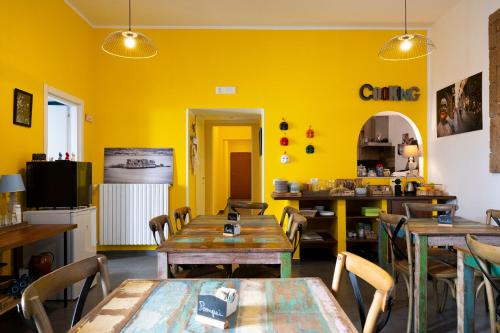 un ristorante con pareti gialle e tavoli e sedie in legno di Palazzo della Loggia B&B a Napoli