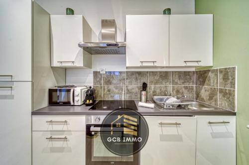 une cuisine avec des armoires blanches et un four à plaques de cuisson dans l'établissement Le Matcha - T2 Cosy Hyper Centre, à Grenoble