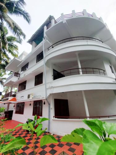 a large white building with a balcony at Udaya Hotel in Vilinjam