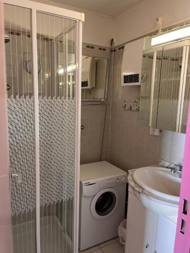 une petite salle de bains avec un lave-linge et un lavabo dans l'établissement Splendide vue mer à 50 m de la plage, à Narbonne