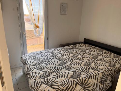 une chambre avec un lit avec une couette noire et blanche dans l'établissement Splendide vue mer à 50 m de la plage, à Narbonne