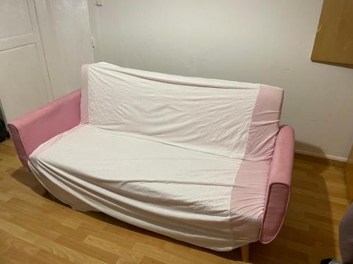 a pink couch covered with a white sheet at Ma maison au cœur de la ville in Bergues