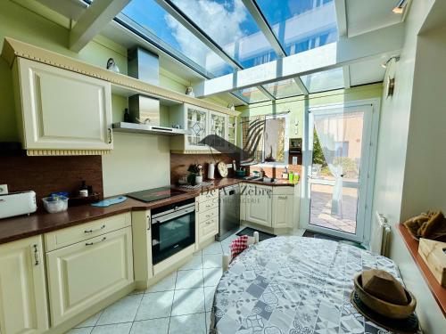 d'une cuisine avec des placards blancs et une grande lucarne. dans l'établissement Le Ferney - Proche du centre-ville et des thermes, à Rochefort