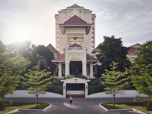 a person walking in front of a large building at Sofitel Phnom Penh Phokeethra in Phnom Penh