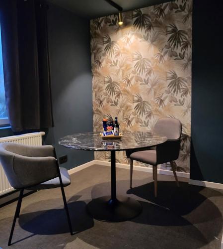 a table and two chairs in a room with a wall at Les studios de la Fontaine in Hornu