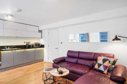 a living room with a purple couch and a table at Apt 3, Soho Apartments 2nd & 3rd floors by Indigo Flats in London