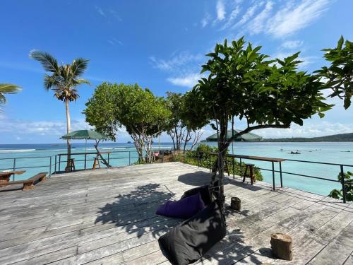 a hammock on a wooden deck with the ocean at Sunset Surfing Villas Mentawai in Tuapejat