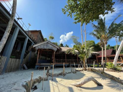 a building on the beach in front of a resort at Sunset Surfing Villas Mentawai in Tuapejat